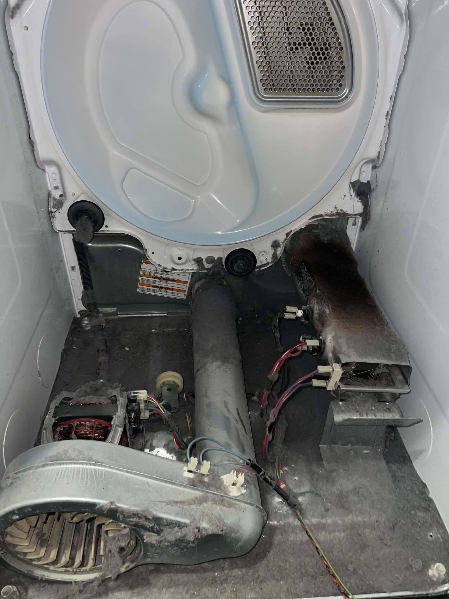 Inside of a dryer packed with lint, before cleaning